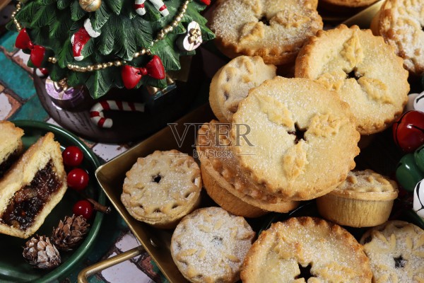 圣诞假日餐桌，摆放着圣诞树、圣诞馅饼和挞 / 节日肉馅甜点，季节性派对美食照片摄影图片