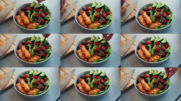 人物,手或碗中盛着沙拉,适合饮食的健康餐或素食小吃,放在家中的厨房桌子上。特写,厨师或烹饪者与番茄、