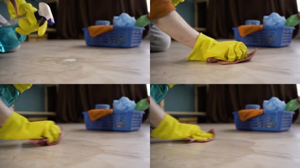 家务，整理和清洁概念。戴着黄色手套的男人在家中用喷雾清洁剂擦拭地板上的灰尘。