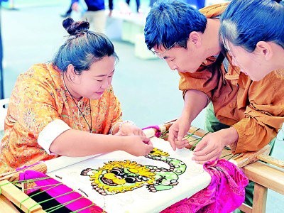 宁夏刺绣自治区级代表性传承人赵静（左）给游客讲解刺绣针法。本报记者 张文攀摄