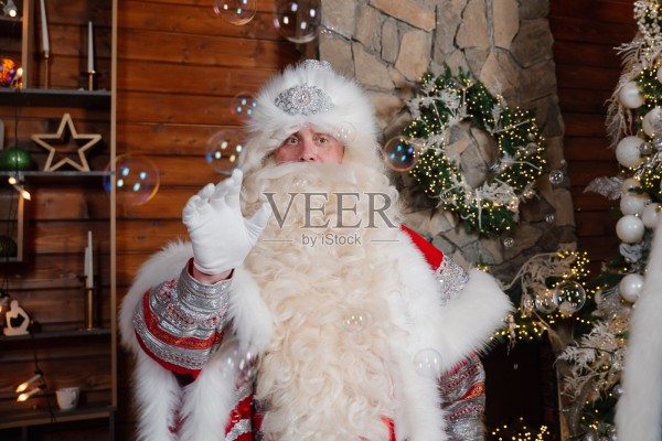 穿着节日盛装的圣诞老人角色在一个舒适的节日环境中吹泡泡照片摄影图片