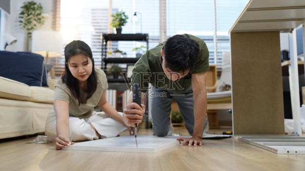 亚洲成年夫妇在现代客厅里一起组装木制家具，创造新的家居装饰，DIY项目，幸福照片摄影图片
