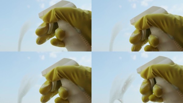 特写镜头喷洒清洁剂在脏窗户上，快速使用对呼吸系统安全的产品清洁家居。高质量4K视频素材。