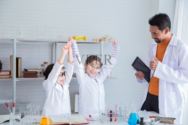 印度老师表扬一位可爱的小学生，她正在科学课上使用现代科技平板电脑应用程序进行实验，并竖起大拇指表示赞赏，这是生活化的教育学习方式。照片摄影图片