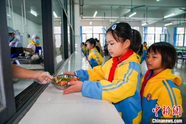 12月26日中午,广西南宁市隆安宝塔实验小学学生在食堂领取营养餐。陈冠言 摄