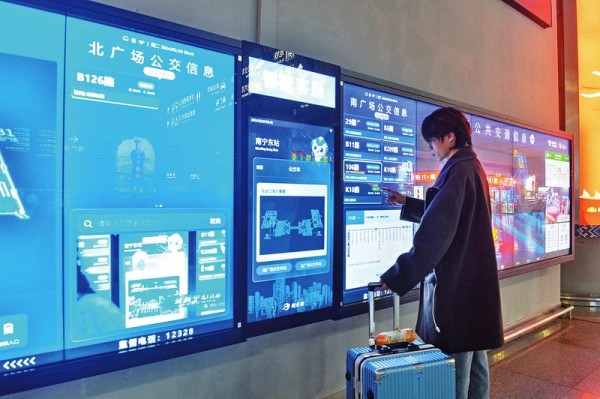 在南宁东站出站口,旅客通过智慧信息屏查询公共交通信息。(黄维业 摄)